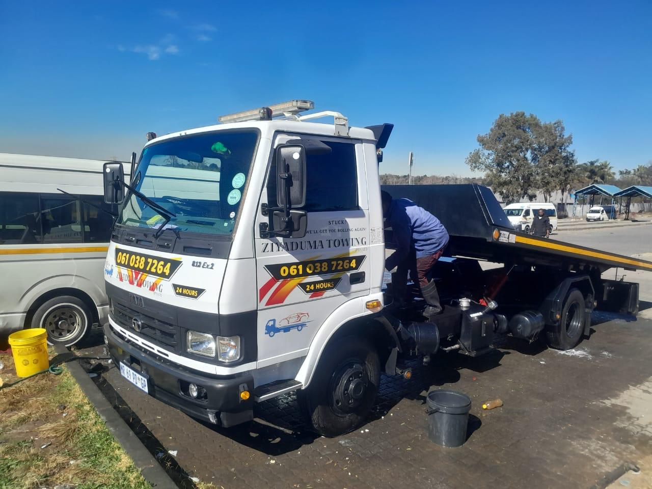 Ziyaduma Towing crew member checking a flatbed tow truck at a roadside stop